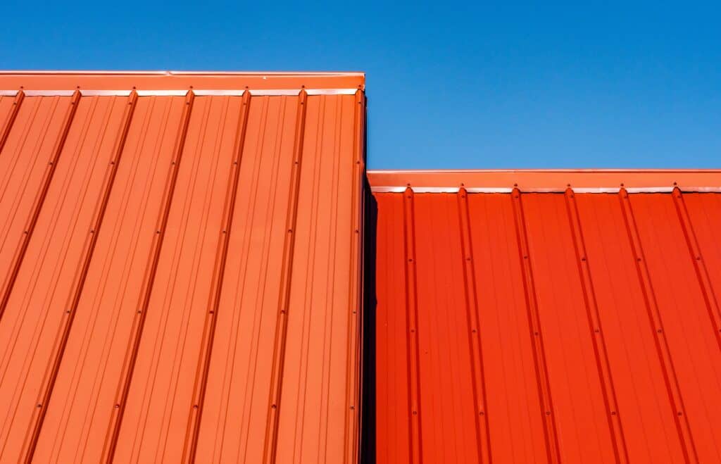 An orange metal roof in front of a cloudless blue sky.