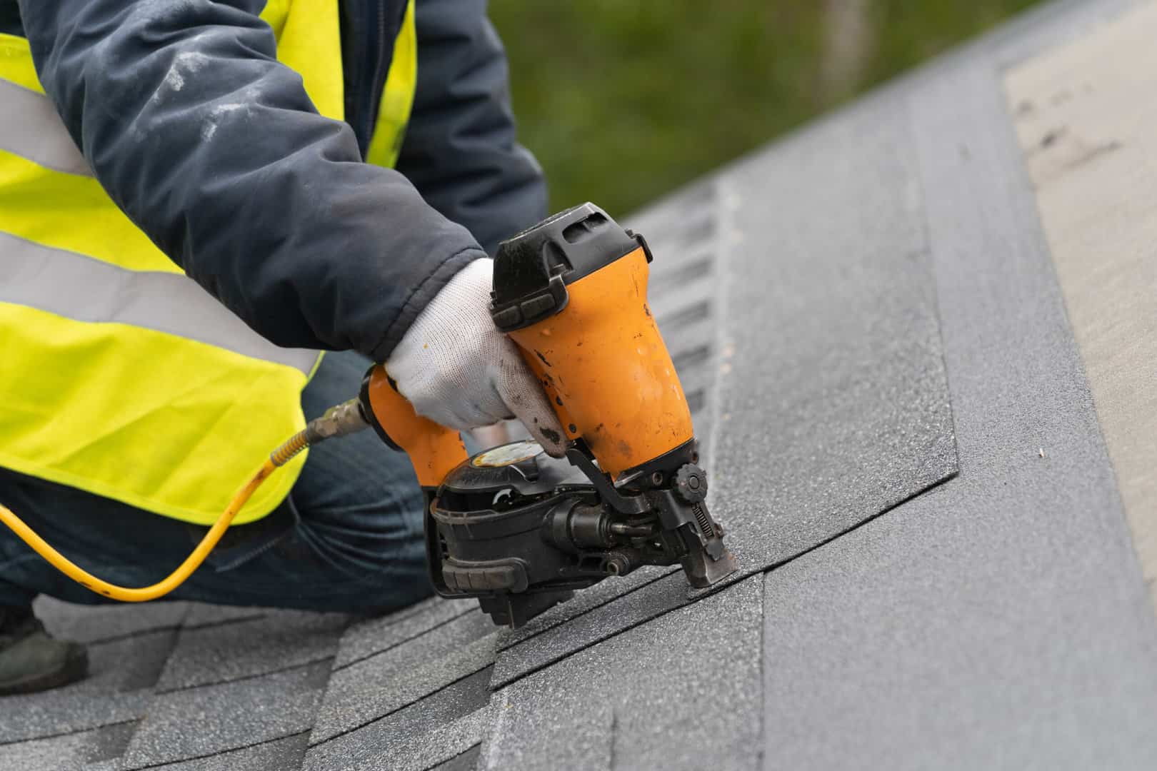 close up of Charlotte roofer nailing in shingles with a roofing nail gun as part of a roof installation in Charlotte