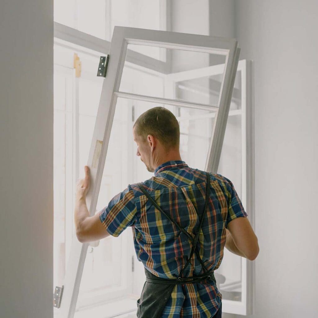 A professional window contractor installing a new window in a Charlotte home.