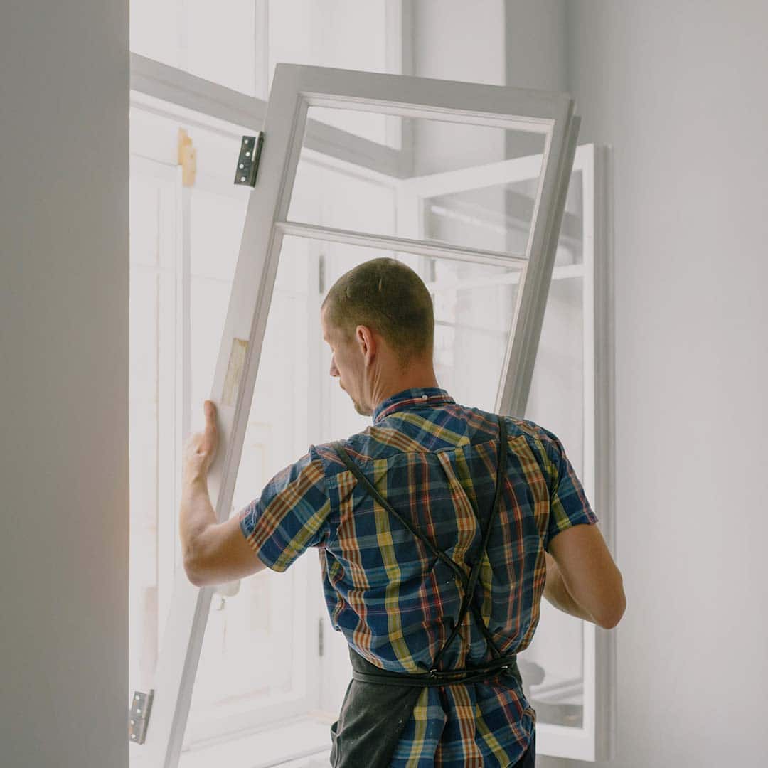A professional window contractor installing a new window in a Minneapolis home.